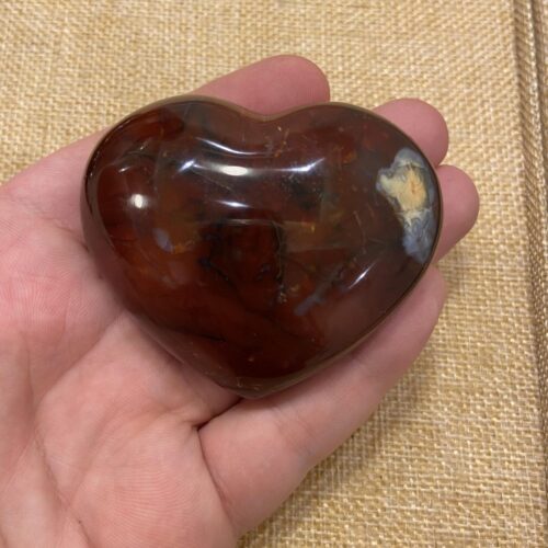 قطعة عقيق احمر شكل قلب علي اليد لتوضيح الحجم