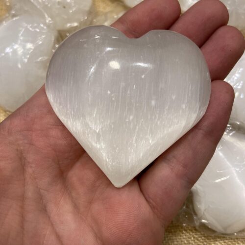 قطعة من حجر السيلينيت علي شكل قلب مصورة علي اليد لتوضيح الحجم